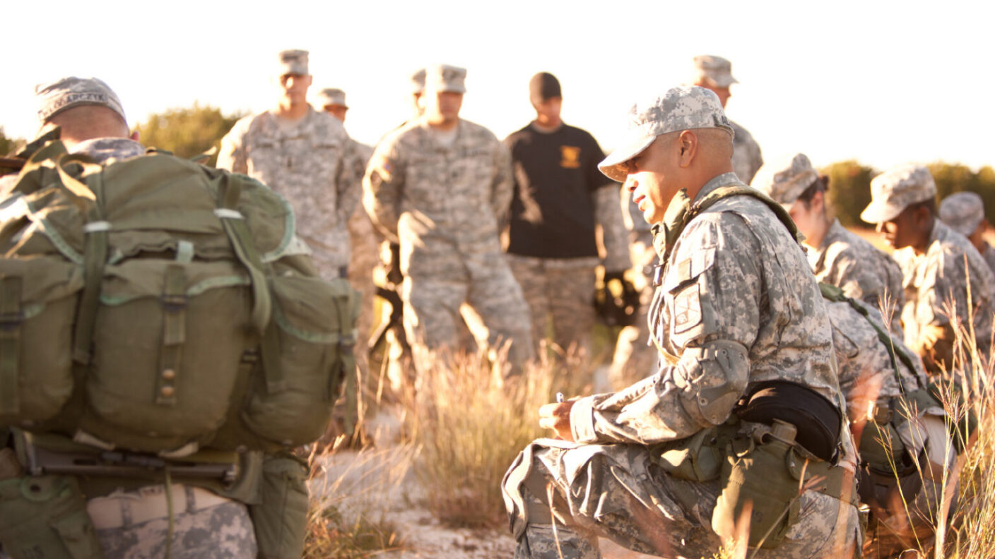 A photo of a group of military soldiers crouching in a field.