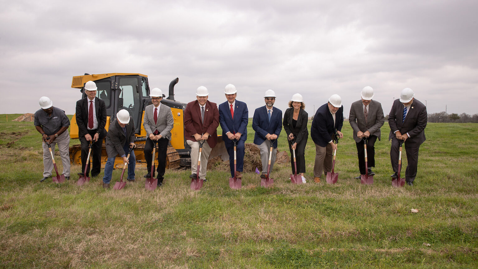 Lineup of a&m officials in a field with shovels and hard hats as a celebration of new construction