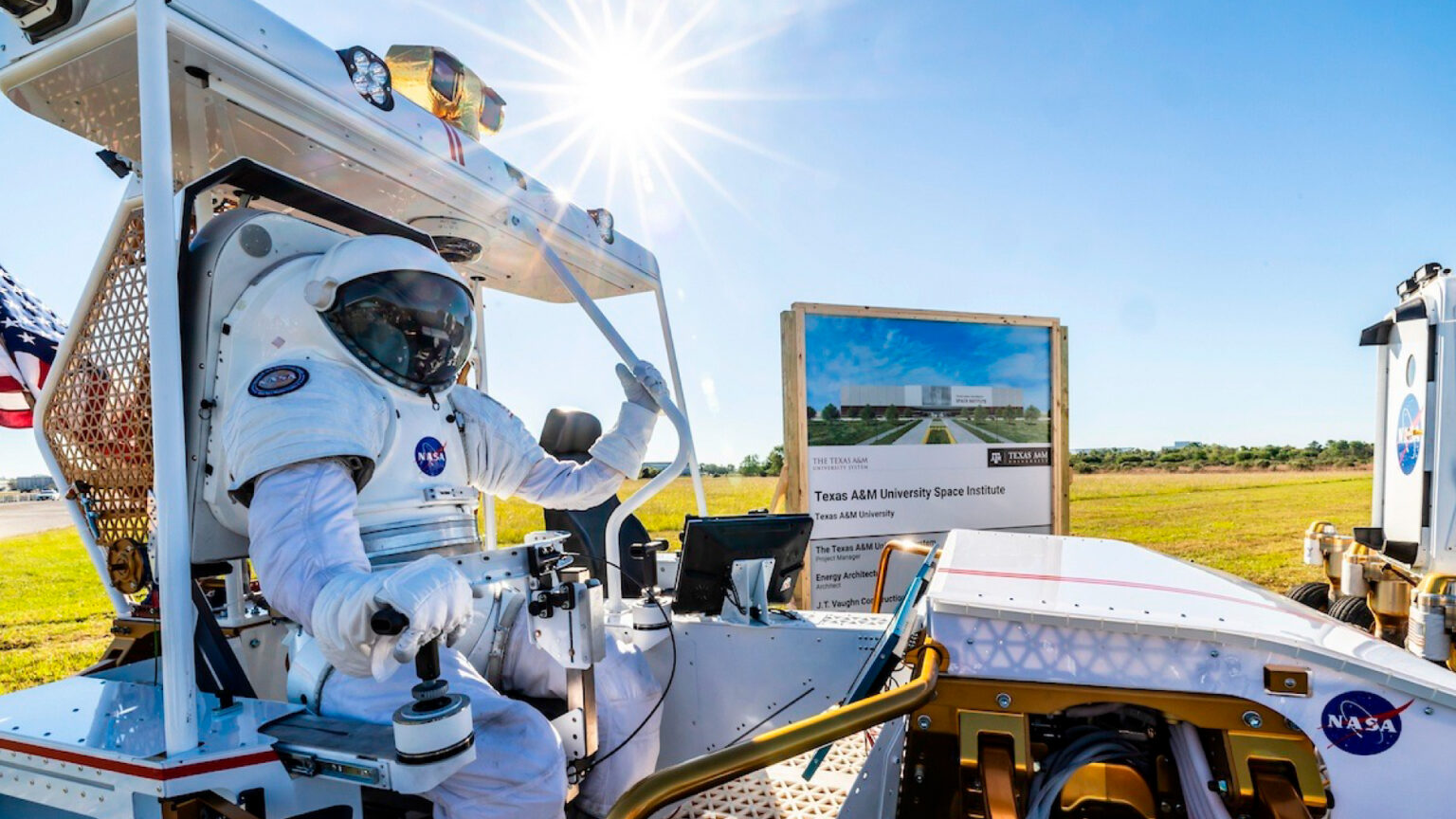 A photo of an astronaut seated in a vehicle in front of the Texas A&M University Space Institute sign.