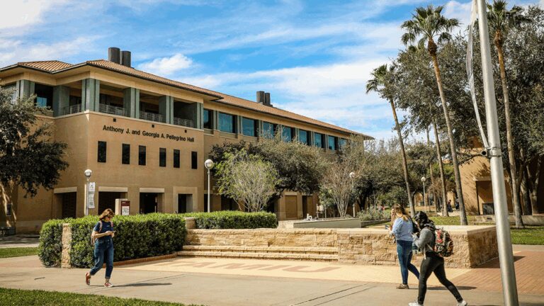 Students walking in front of a Texas A&M International University campus building.