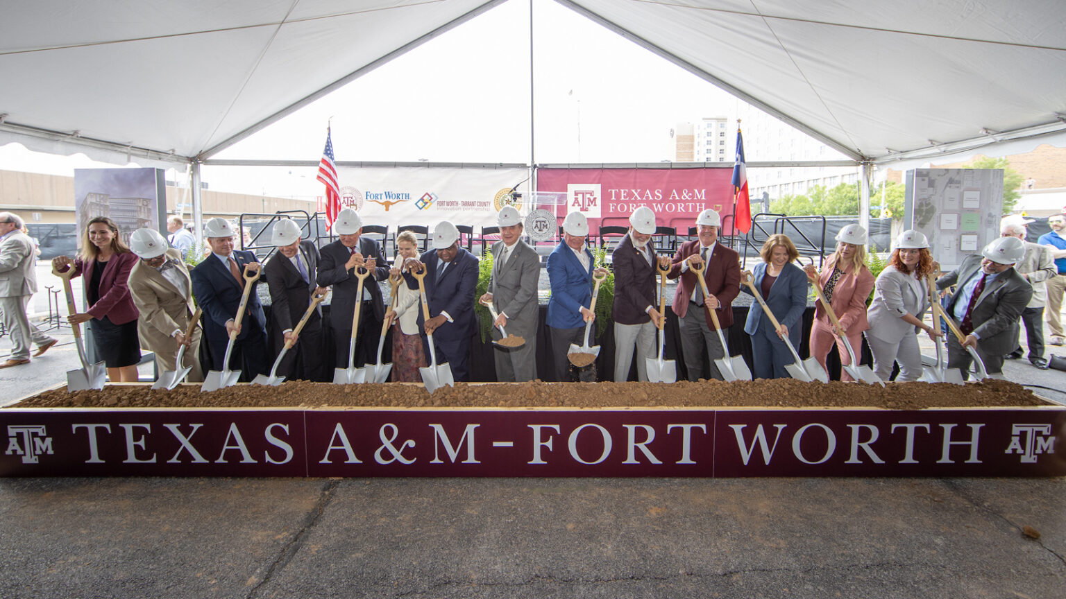 picture of an celebration of the first building starting construction, many representatives of the campus in hard hats and shovels in front of a decorative dirt station