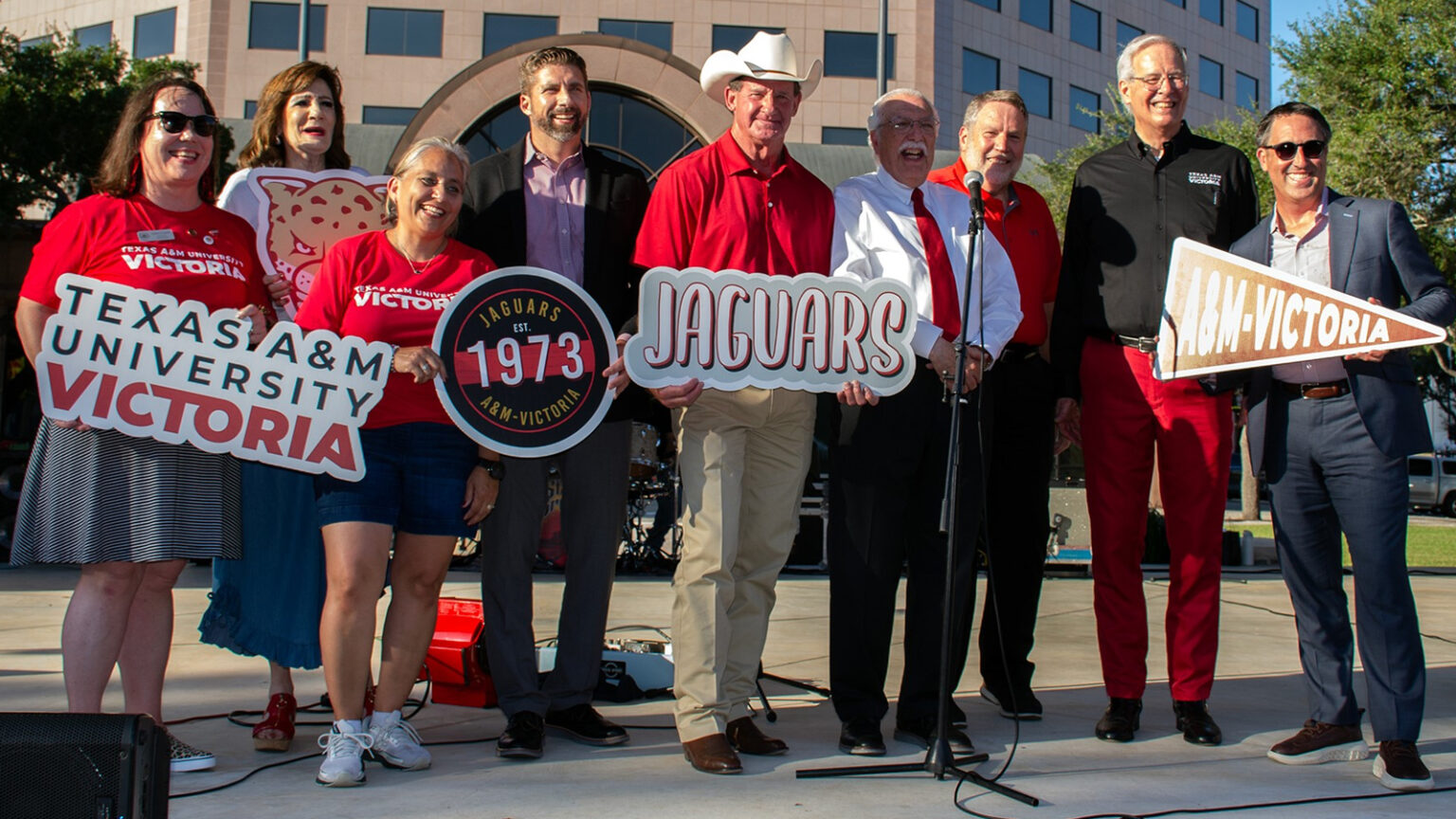 A photo of a group of people holding promotional signs at Texas A&M University-Victoria.